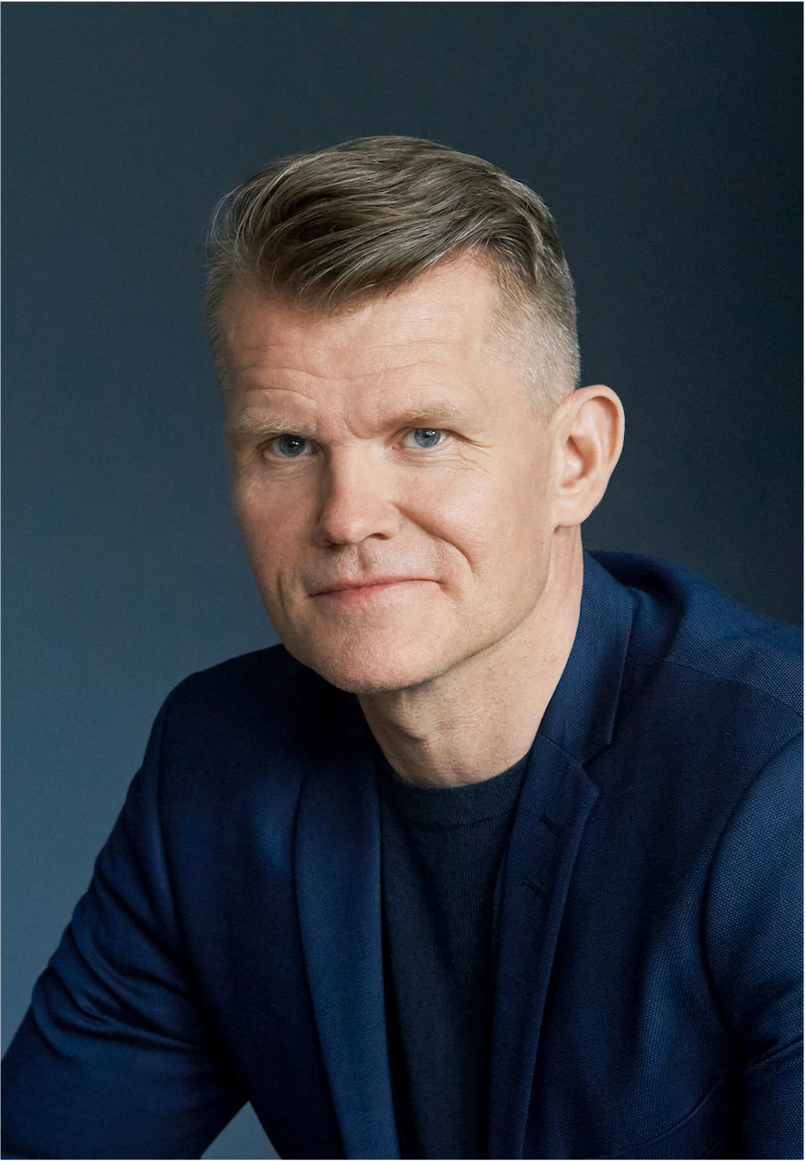 Portait of Árni Blöndal, A member of Axely'fs Board of Directors; a middle-aged man with short, gray hair, blue eyes, wearing a dark blue blazer and a black shirt, set against a dark background.